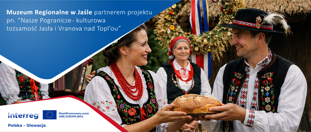 Baner promocyjny projektu Interreg Polska–Słowacja. Po lewej stronie na niebieskim tle widoczny napis informujący, że Muzeum Regionalne w Jaśle jest partnerem projektu „Nasze Pogranicze – kulturowa tożsamość Jasła i Vranova nad Topľou”, a na dole logotypy Interreg i Unii Europejskiej. Po prawej stronie scena folklorystyczna: kobieta i mężczyzna w tradycyjnych strojach ludowych uśmiechają się do siebie, trzymając wspólnie okrągły bochen chleba. W tle stoją inne osoby w strojach ludowych oraz dekoracje z suszonych roślin i kwiatów.